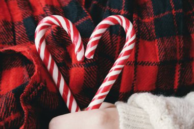 Kalp şeklinde şeker kamışlı kırmızı Noel bastonları tutan bir kadın.