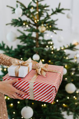 Noel 'i büyük ve küçük paketlenmiş hediye kutularıyla ve bulanık bir yılbaşı ağacıyla kutluyor.