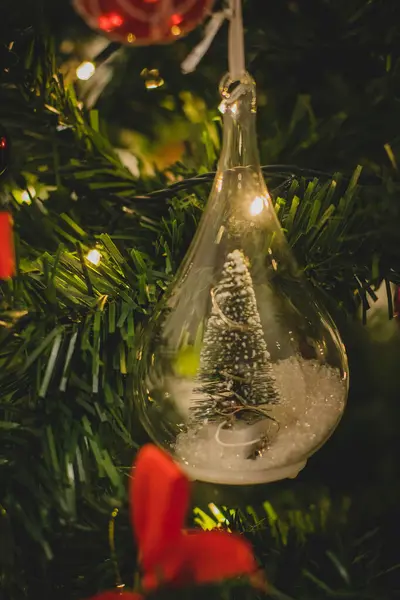 Kristal cam şişesinde biraz kar olan süslü bir Noel Ağacı.