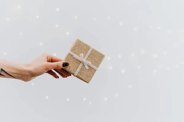  Kahverengi Noel hediyesi kutusu tutan bir kişi.