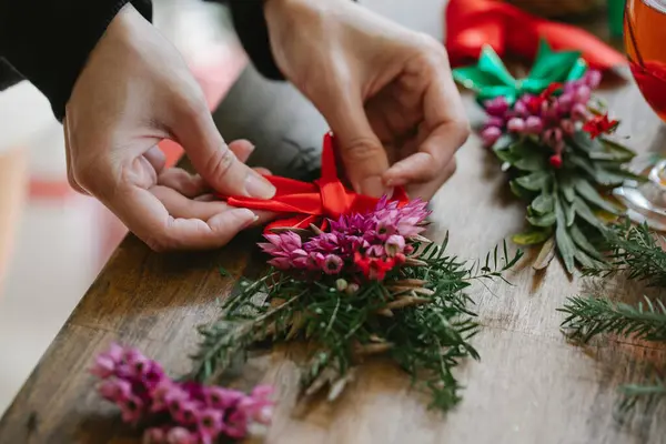 Bir insan birine Noel dilemek için buket çiçek hazırlıyor.