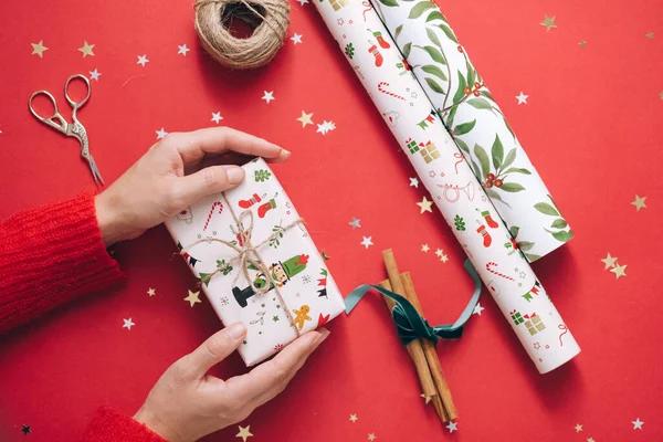 Noel hediyesi kutusunu paketlenmiş bir hediye kağıdıyla tutan kişi.