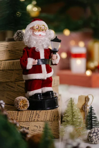 Noel Baba bir yığın hediye kutusunun üzerinde oturuyor. Noel resimlerine sarılmış kağıtlarla.