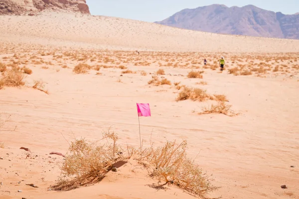 Wadi rum, Jordan - 5th October, 2022: flag and Athlete competitors fast walk in desert pass markings on extreme hot in challenging Ultra X Jordan multi-stage ultramarathon