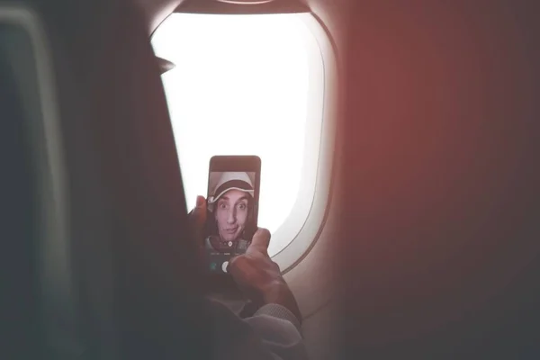 若い白人女性の乗客のポーズのための自撮りタッチスクリーンスマートフォン機内座席の前にフライト 面白い女の子の休暇の投稿のソーシャルメディアの概念 — ストック写真