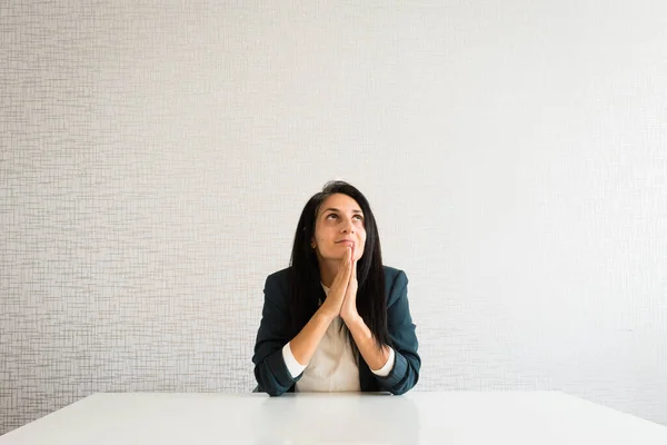 stock image Young caucasian brunette business woman director in office pray for help hopeful in office behind desk for success and praise at work