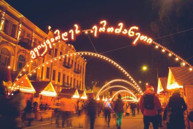 Tiflis, Gürcistan - 25 Aralık 2021: Noel günü çocuklu sokak manzaralı kalabalık Noel pazarında. Kutlamalar ve şehir tatili ruhu