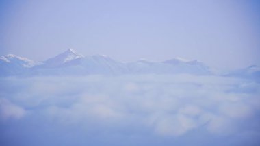 Karlı dağ sisi ve bulutlar karlı zirvelerin altında katmanlar oluşturur. Dağlardan geçen bulutları oluşturan uzay bayrağını kopyalayın. Tusheti Dağları Panorama