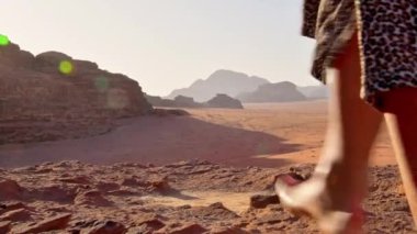 İnce, beyaz tenli kadın turist, kayalıklarda çıplak ayakla gün doğumunu seyrediyor ve Bedevi kamp alanındaki Wadi rom Panorama 'da tatilin tadını çıkarıyor. Ürdün 'de Popüler Wadi Rum Çölü