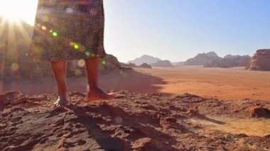 İnce, beyaz tenli kadın turist, kayalıklarda çıplak ayakla gün doğumunu seyrediyor ve Bedevi kamp alanındaki Wadi rom Panorama 'da tatilin tadını çıkarıyor. Ürdün 'de Popüler Wadi Rum Çölü