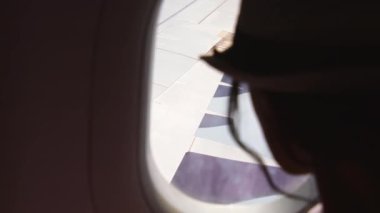 Kafkas kadınının siluetini kapat ve uçan bir uçağın penceresinden dışarı bak. Uçağın yolcusu pencerenin yanında dinleniyor.