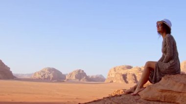 Kadın turist Wadi Rum Çölü 'nde çıplak ayakla uçurumun kenarında oturuyor. Vadi Saabit vadisinde. Jordan kavramı keşfet