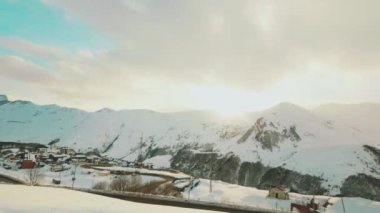 Gudauri köyünün hava manzaralı kamyonları, dağ manzaralı karlı koşullarda naklediliyor.