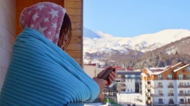 Bakuriani, Gürcistan - 5 Mart 2022: Gürcistan 'daki Bakuriani kayak merkezindeki Holiday apartmanının balkonunda sabah kahvesi içen beyaz kadın turist