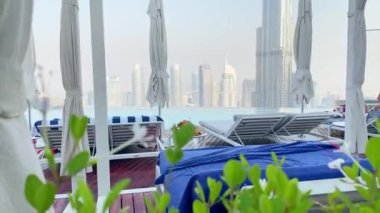 Dubai, BAE - 17 Ekim 2022: Turistler rahat bir şekilde çatı katındaki havuz kenarında oturuyorlar. Lüks tatil beldesi ünlü Sky view Oteli