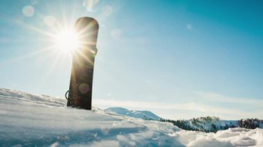 Close up black base of snowboard in snow with white mountains in the background. Skiing snowboarding banner vertical panorama