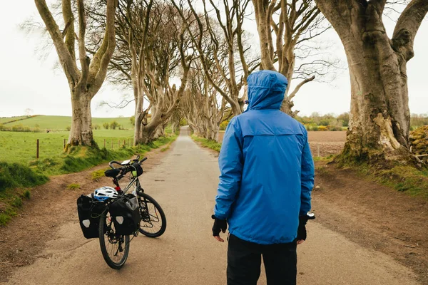 Touring bicycle set up with panniers. dark hedges in Northern Ireland. Traveler male stand by bicycle visit famous landmarks in Northern Ireland