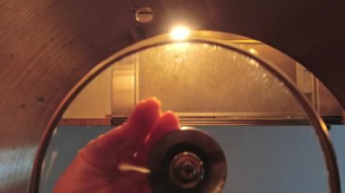 Female hand close pot lid prepare food at home. Modern household and cleanliness in kitchen. Creative low angle view generic pot and food preparation concept