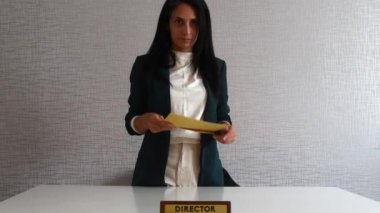 Beyaz tenli genç, esmer kadın, ofis yöneticisi. İş sözleşmesi ya da anlaşma imzala, maaş bordrosu sarı zarf ve gülümse.