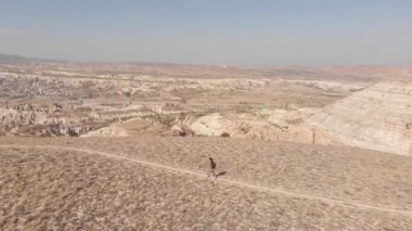 Panning aerial view young sporty hiker woman go up trail outdoors with scenic nature panorama