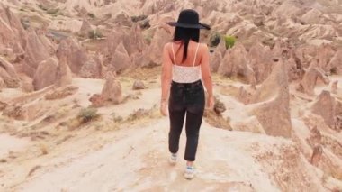 Beyaz kadın turist özgürlüğün ve tatilin tadını çıkarıyor. Kapadokya 'nın yıkık vadisindeki peri bacalarının arasında geziyor.