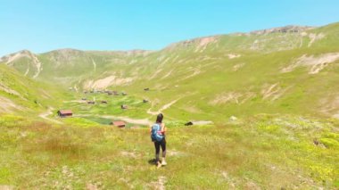 Aerial view woman hike by Shuamta small lake surrounded by mountain village wooden houses in high Adjara