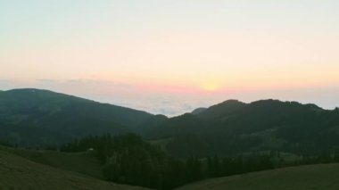 Static aerial panoramic view of sun rising above horizon with clouds above forest. Weather and forecast background