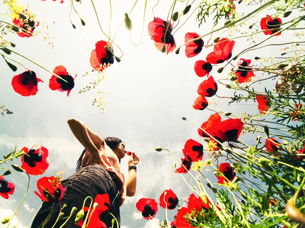Girl smell flower in poppy field. Dreamy girl in love outdoors. Low angle creative photography