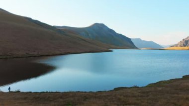 Side static view caucasian woman walk on hiking trail outdoors hike by scenic blue alpine lake