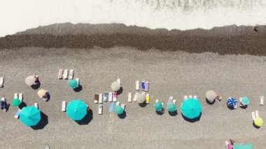 Aerial top view people at Sarpi Beach in Batumi under umbrellas in hot sunny day.