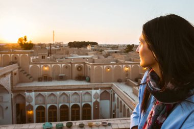 Yazd, Iran - 19th june, 2022: portrait of caucasian visitor tourist watch sunset in traditional rooftop cafe relax enjoy panoramic views of old town