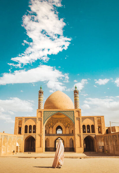 Кашан, Иран - 29 мая 2022 года: Туристка в специальном халате посетит красивую мечеть Ага Бозорга в солнечный день