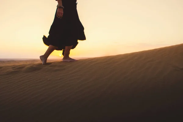 Low angle tracking view beautiful woman in long dress feet follow walk on KAshan desert dunes