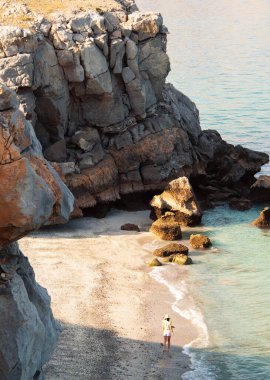 Havadan bakıldığında, bikinili turist kadın İran Körfezi 'ndeki beyaz kumsalda yalnız başına yürüyor. Musandam. Umman.