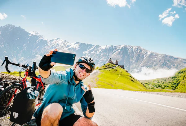 Male person takes selfie on solo bicycle touring vacation in scenic caucasus mountain region. Cycling adventure holiday destination and travel selfie in nature