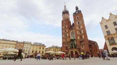 Krakow, Polonya - 6 Mart 2023: St. Mary bazilikası ve tarihi Polonya şehri mimarisi ile Krakow ana meydanının dinamik zaman kaymasını yakınlaştır