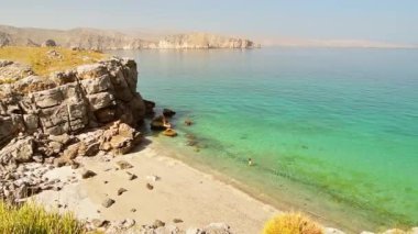 Havadan bakıldığında, bikinili turist kadın İran Körfezi 'ndeki beyaz kumsalda yalnız başına yürüyor. Musandam. Umman.