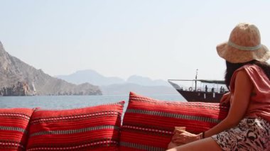 Musandam, Orman - 15 Şubat: Tekne turundan keyif alan kadın turist güvertede uzanmış İran körfezi geçmişiyle gülümserken, yolcuları el sallıyor