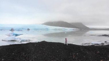 Fjallsjokull 'un buzul gölünü kapatın. Buzdağının üzerinde insan var. İzlanda 'daki muhteşem buzul gölü eriyor.