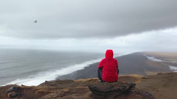 人们坐在岩石上沉思地看着大西洋的海浪 著名的标志性悬崖观点对雷诺斯法哈拉黑色沙滩 为旅行寻找方向和目的的人 — 图库视频影像