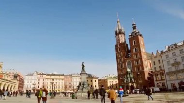 Krakow, Polonya - 6 Mart 2023: Krakow Meydanı 'nın ana turistik gezisi güneşli bahar gününde Rynek Glowny. Ünlü St. Marry Bazilikası. Avrupa 'da tarihi 2. Dünya Savaşı kenti