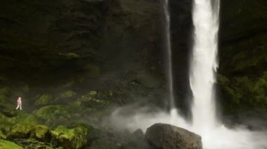 İzlanda 'daki ünlü gezi merkezi Kvernufoss şelalesinden kadın ziyaretçi ziyareti. Bahar mevsiminde ünlü bir tatil beldesi. Turistik yerleri keşfetmek doğal harikalar yaratır.