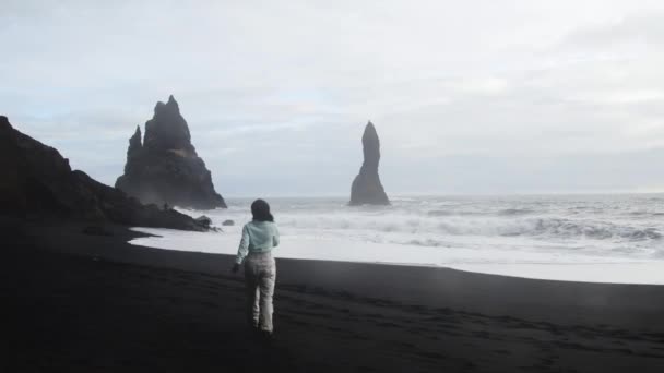 春天的时候 白人女游客一个人在黑沙滩上散步 雷尼斯法哈拉 紧靠着海浪和著名的悬崖峭壁 — 图库视频影像