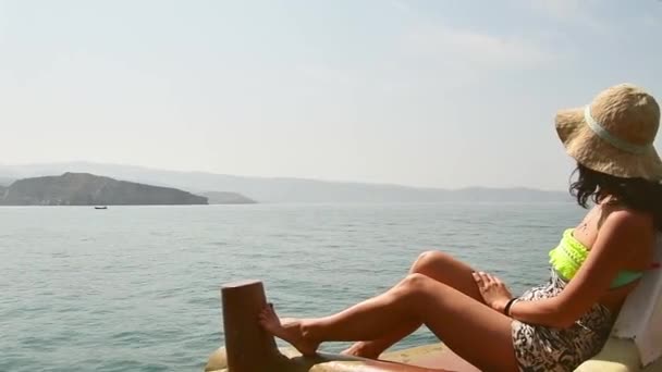 白种人女游客放松地躺在游轮甲板上度假 享受着阳光灿烂的波斯海湾美景和岩石山崖 阿曼中部的度假目的地 Musandam — 图库视频影像