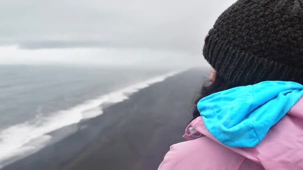 在外面多风的天气里 独自站在海边凝视着一个高加索女人 冰岛黑色沙滩大西洋著名观点 — 图库视频影像
