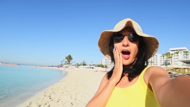 若い白人旅行者やインフルエンサーは 日当たりの良いビーチで自撮りを取ります 口カバービーチポーズショックを受けている休暇ポーズソーシャルメディアの話楽しい時間 — ストック動画