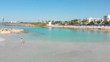 Kıbrıs 'ın güzel Nissi plajında hava manzaralı kadın turist yürüyüşü. Meşhur seyahat yeri. Ünlü beyaz kum plajı. Yalnız gezgin Nissi adasını ziyaret ediyor.