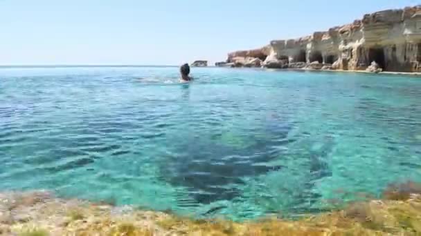 妇女在阿亚纳帕湾北部海岸游泳 浅蓝色的浅水 平静的海景和岩石海岸 海鸥热门旅游目的地 — 图库视频影像