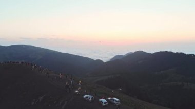 People on famous Bakhmaro sunset viewpoint watch sunset over clouds in Georgia