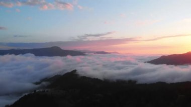 Adjara bölgesindeki bulutlar üzerinde gün batımının dramatik görüntüsü bulutlar geçiyor ve ufukta güneş parlıyor. Köknar ağacı ormanı üzerinde büyüleyici bir günbatımı arkaplanı var.